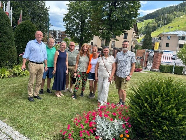 Gruppe von Menschen vor Gebäuden und Berglandschaft in Österreich